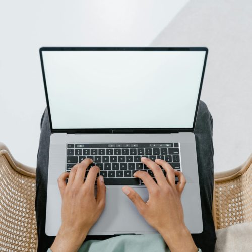 Top view of someone using a laptop with a blank screen, perfect for mockup and tech concepts.